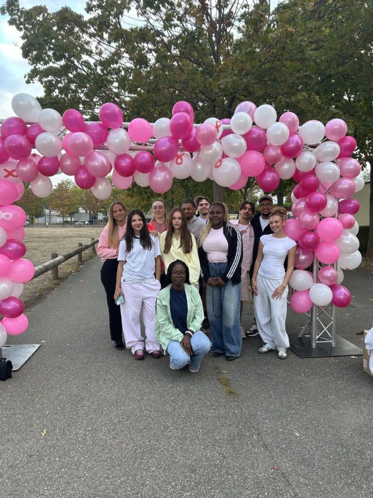 Étudiants de TIHS Business School bénévoles à Colmar pour Elles 2026, sous l'arche de ballons roses